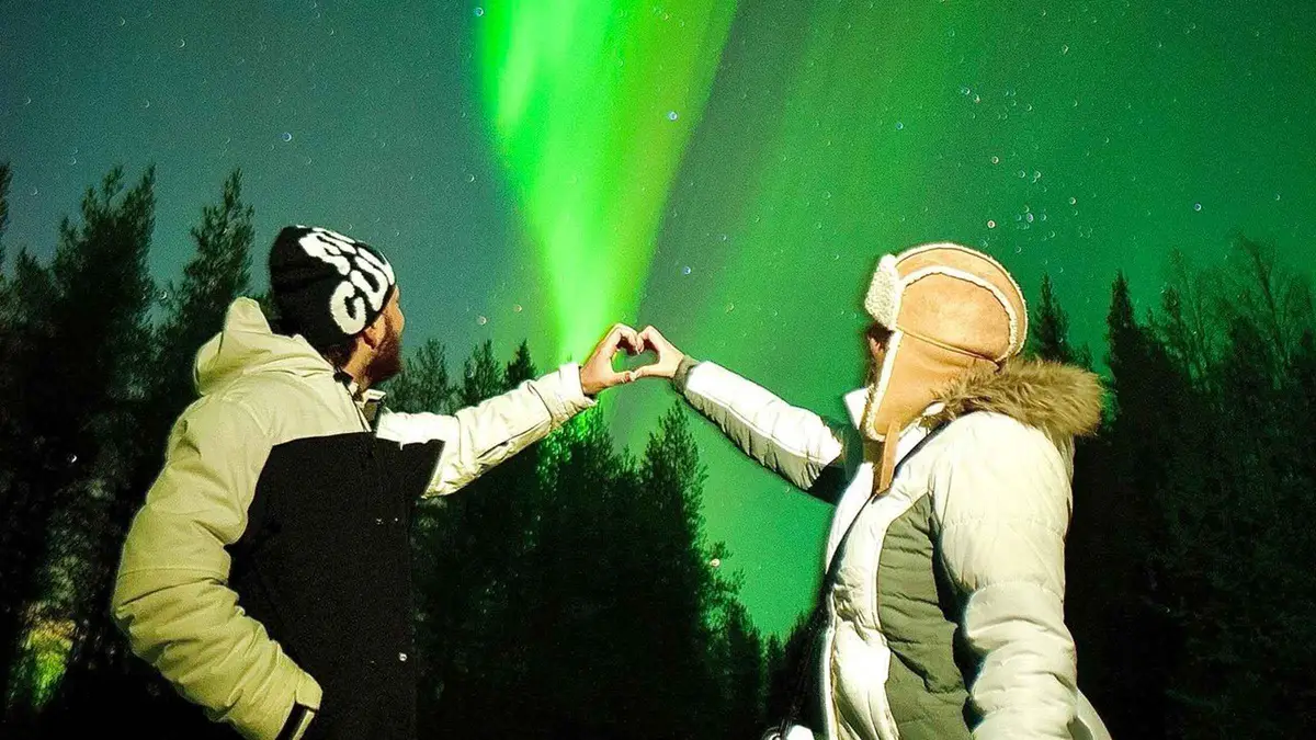 Photographer capturing travellers under the northern lights on a small-group photography aurora borealis tour Rovaniemi, Finnish Lapland