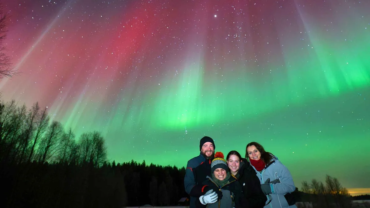 Heated VIP van parked on a snowy roadside under green northern lights on a re-do guaranteed aurora borealis tour Rovaniemi, Lapland